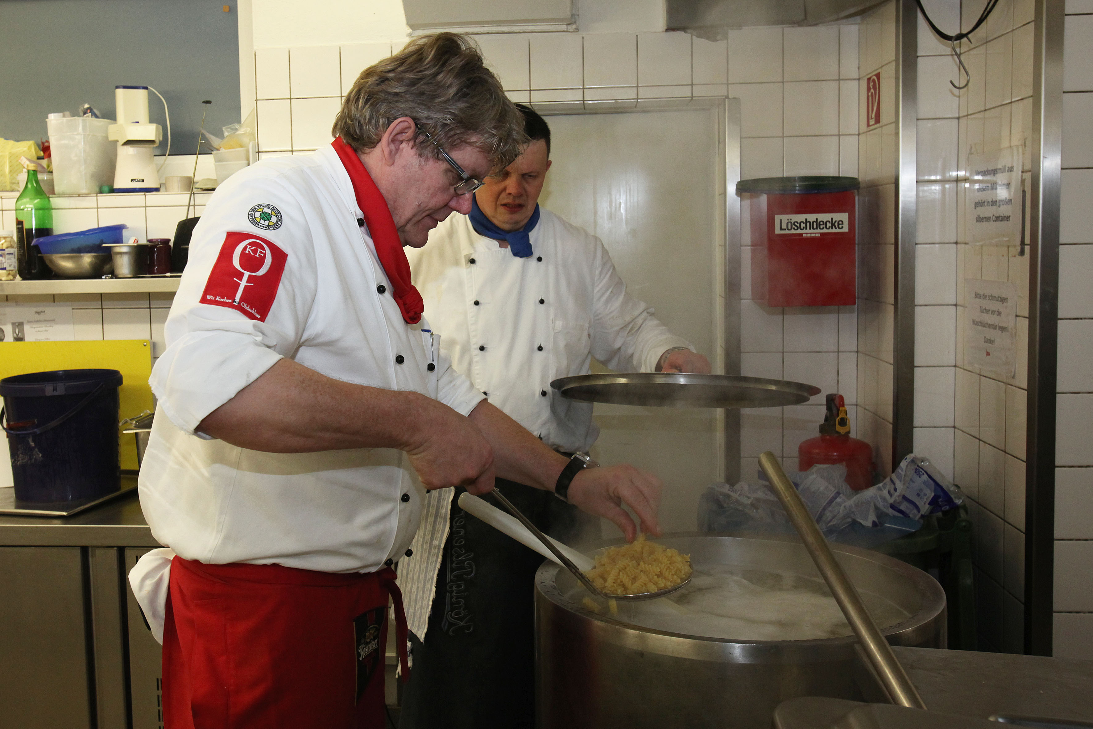 Cord Kelle (links) rührt einen Topf mit 25 Kilo Nudeln um. Mit dem Verein "Kochen für Obdachlose" kocht der Hotelinhaber aus Langenhagen von Dezember bis Mitte März ehrenamtlich für Obdachlose und Bedürftige. Bild: epd-bild/Harald Koch